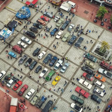 Luftaufnahme eines belebten Platzes mit Fahrzeugen und Fußgängern.